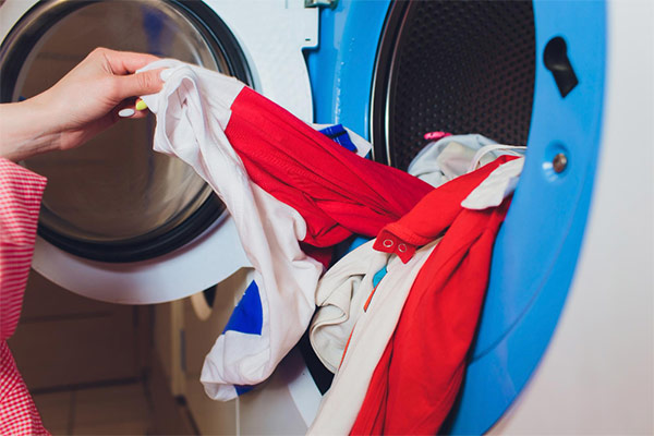 A person loading clothes into a washing machine.